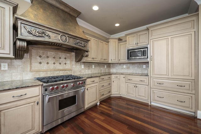 kitchen with light stone countertops, premium range hood, cream cabinetry, stainless steel appliances, and dark wood-style flooring