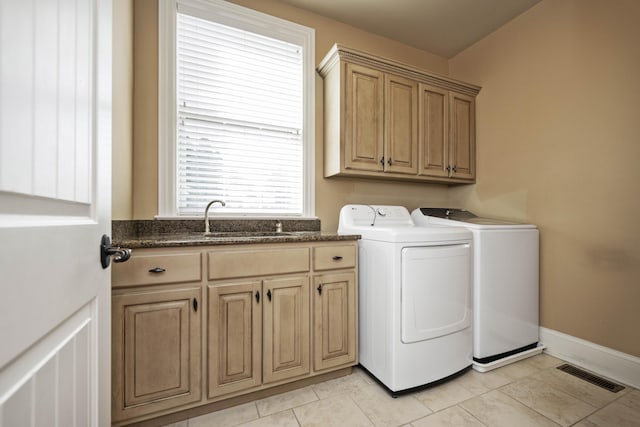 clothes washing area featuring visible vents, baseboards, separate washer and dryer, cabinet space, and a sink