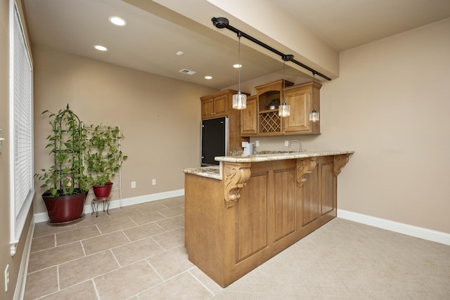 kitchen with light stone counters, black fridge, a peninsula, a kitchen breakfast bar, and hanging light fixtures