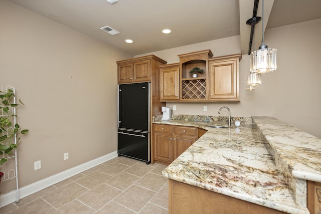 kitchen featuring visible vents, a sink, light stone countertops, black fridge, and open shelves