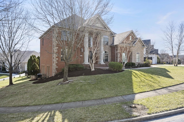 neoclassical home with brick siding and a front yard