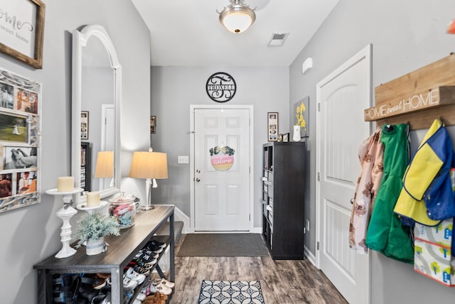 foyer entrance with dark wood finished floors, visible vents, arched walkways, and baseboards