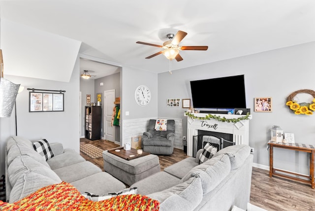 living room with a fireplace, baseboards, ceiling fan, and wood finished floors