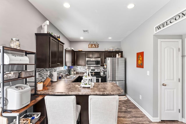 kitchen featuring backsplash, visible vents, dark brown cabinetry, and appliances with stainless steel finishes