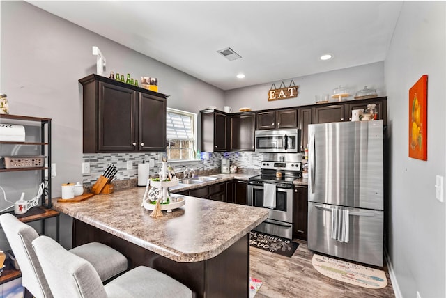 kitchen featuring visible vents, a sink, decorative backsplash, dark brown cabinets, and appliances with stainless steel finishes