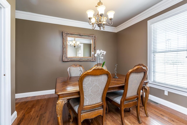 dining area featuring wood finished floors, baseboards, ornamental molding, and an inviting chandelier