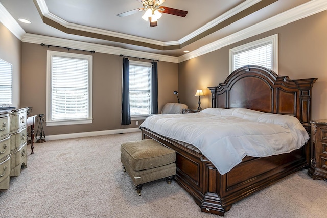 bedroom featuring a raised ceiling, light colored carpet, and multiple windows