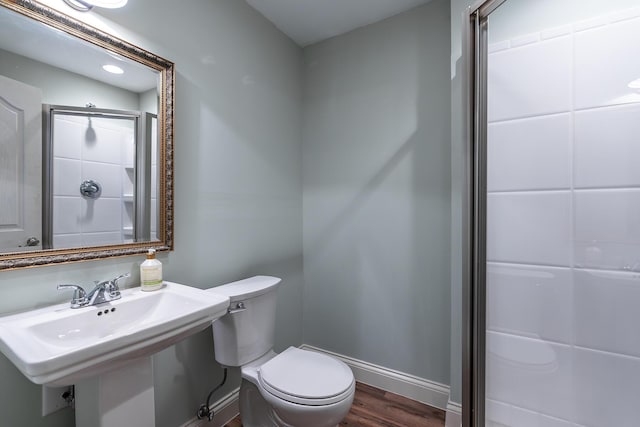 bathroom with toilet, wood finished floors, a sink, a shower, and baseboards