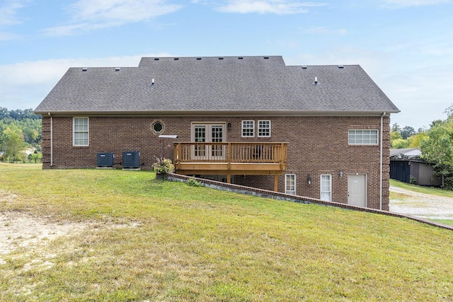back of property with brick siding, a lawn, a shingled roof, and a deck