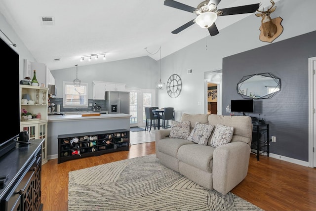 living room with light wood-type flooring, visible vents, baseboards, and a ceiling fan