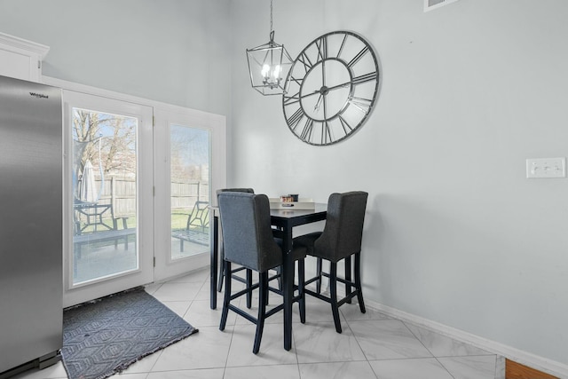 dining area with a chandelier, baseboards, and a towering ceiling