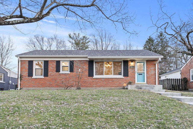 view of front of house with brick siding, a front lawn, and roof with shingles