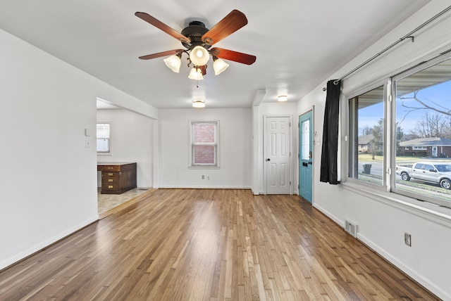 unfurnished living room featuring light wood-style floors, visible vents, a wealth of natural light, and baseboards