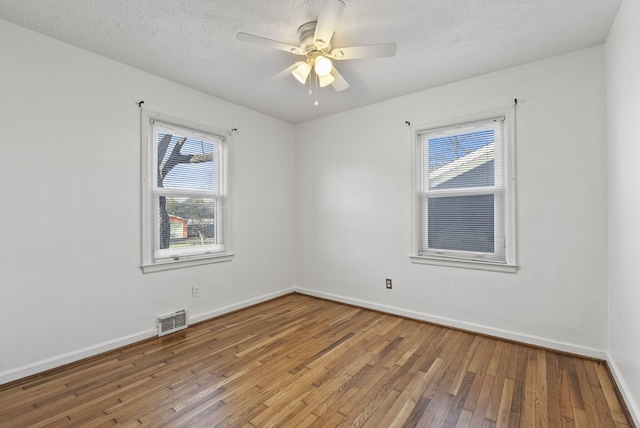 spare room with visible vents, a ceiling fan, baseboards, and hardwood / wood-style floors