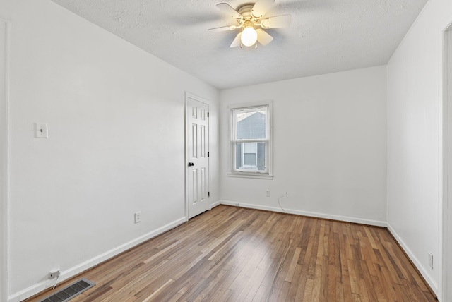 unfurnished room with visible vents, baseboards, a textured ceiling, and hardwood / wood-style flooring