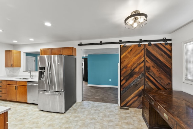 kitchen with recessed lighting, a sink, light countertops, appliances with stainless steel finishes, and a barn door