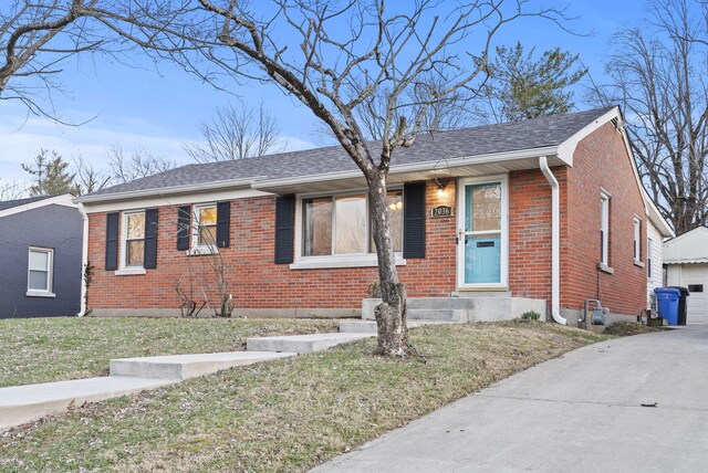 view of front of home featuring a front yard, brick siding, and roof with shingles