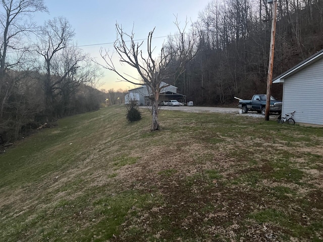 yard at dusk featuring a forest view