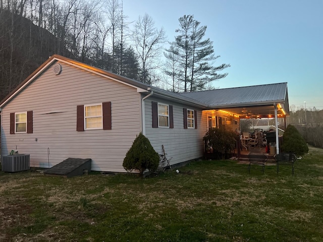 back of property with a yard, central AC, and metal roof