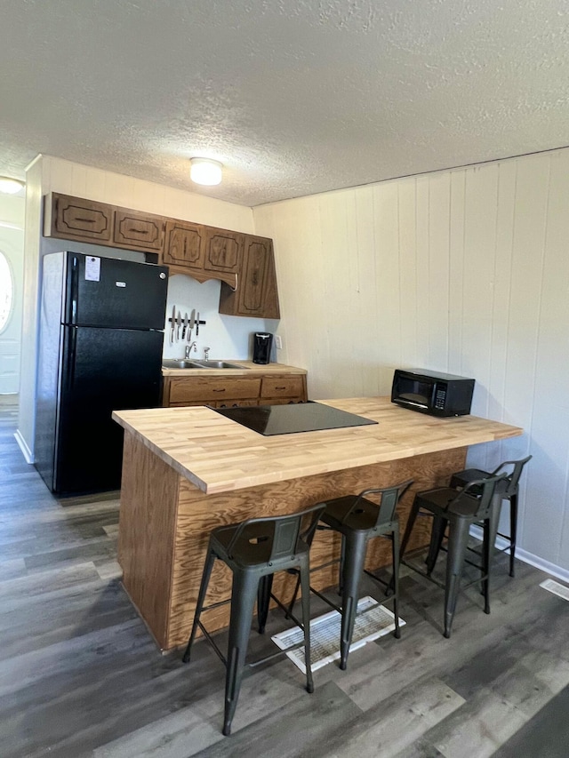 kitchen featuring visible vents, dark wood-style flooring, black appliances, a textured ceiling, and wood counters