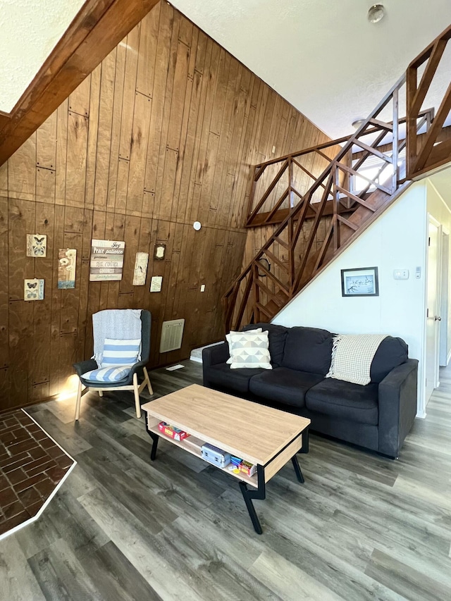 living room with stairway, wood finished floors, and wood walls