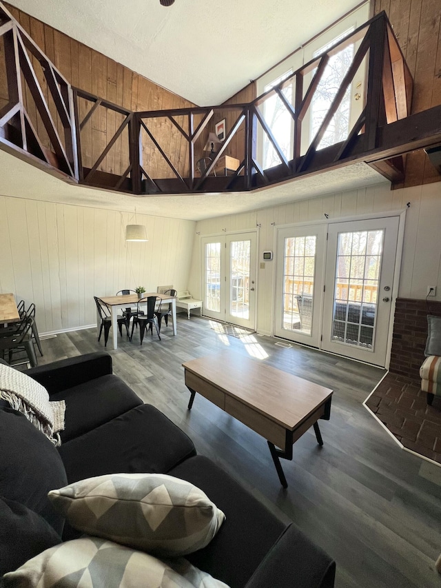 living room with high vaulted ceiling, wood finished floors, and wooden walls