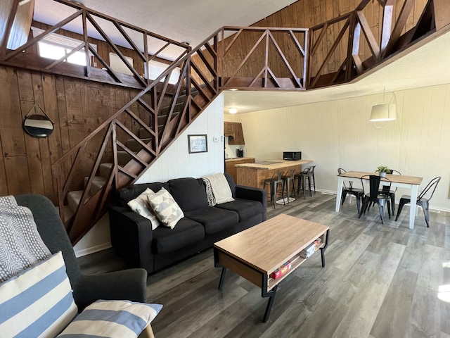 living room with wood finished floors, stairs, and wood walls