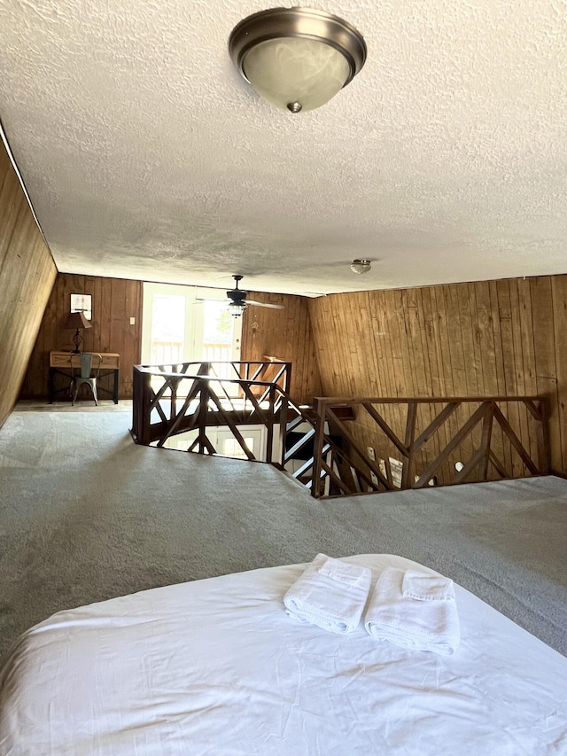 carpeted bedroom featuring wooden walls and a textured ceiling