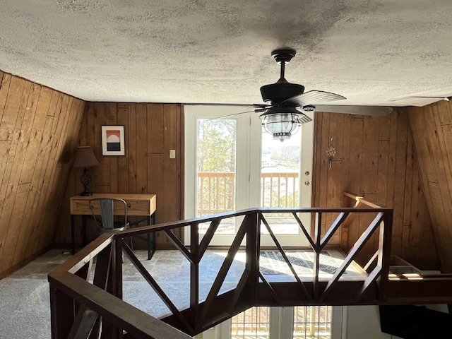 stairway featuring a wealth of natural light, a textured ceiling, and wood walls