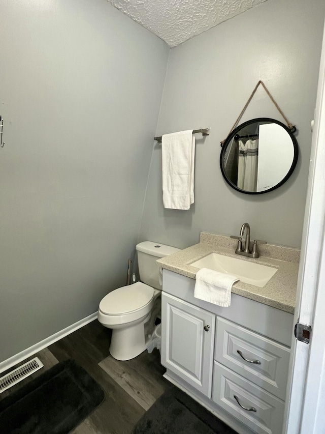 bathroom with vanity, wood finished floors, visible vents, a textured ceiling, and toilet