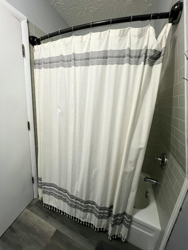 full bath with shower / bathtub combination with curtain and a textured ceiling