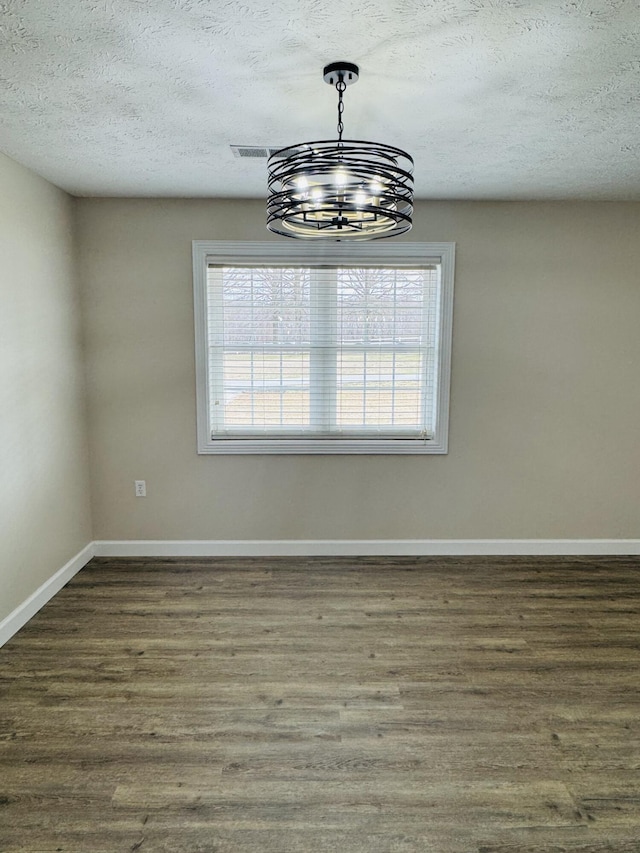 unfurnished room with wood finished floors, baseboards, and a textured ceiling