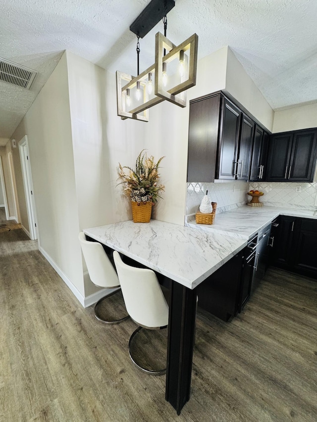 kitchen with tasteful backsplash, wood finished floors, visible vents, and baseboards