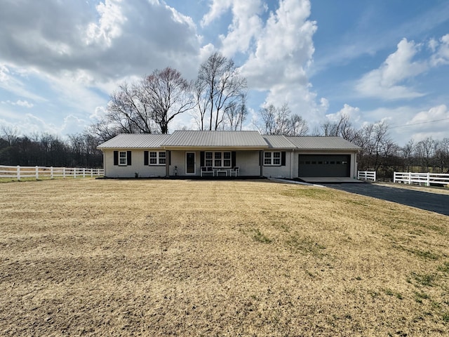 ranch-style home featuring brick siding, fence, metal roof, driveway, and an attached garage