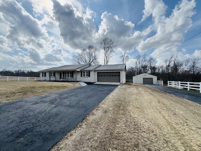 view of front of property featuring an attached garage, fence, a front yard, metal roof, and driveway