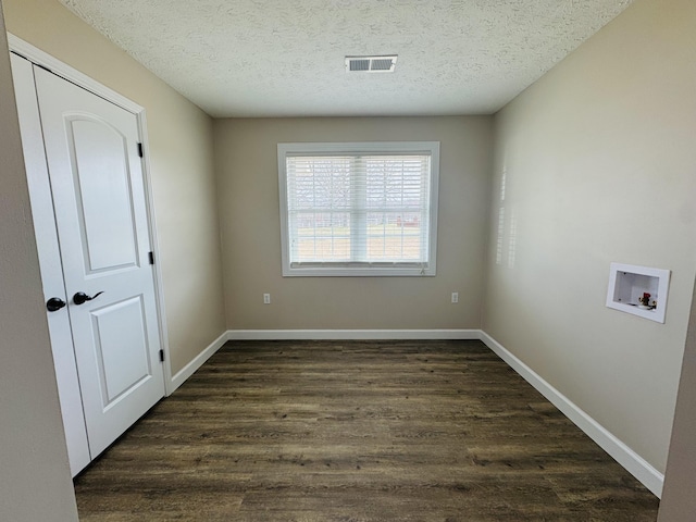 empty room featuring baseboards, visible vents, dark wood-style flooring, and a textured ceiling