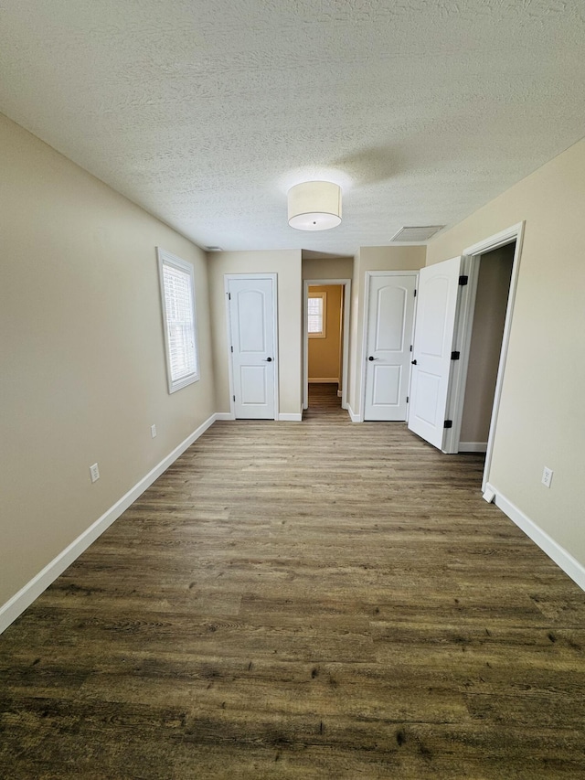 unfurnished bedroom featuring dark wood finished floors, a textured ceiling, and baseboards