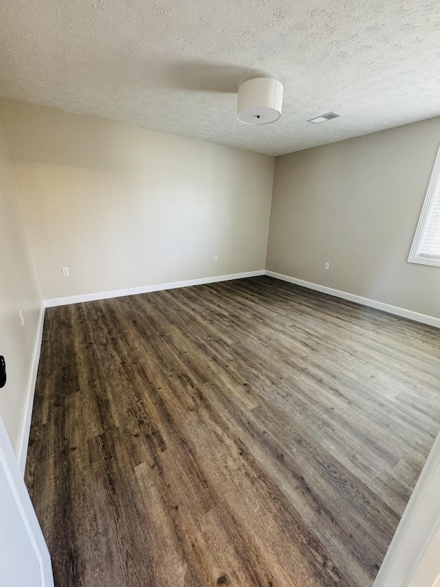 unfurnished room with wood finished floors, baseboards, and a textured ceiling