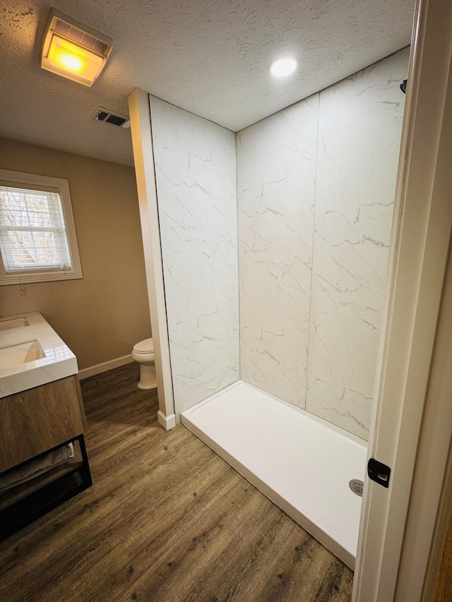 bathroom featuring toilet, wood finished floors, visible vents, and a textured ceiling