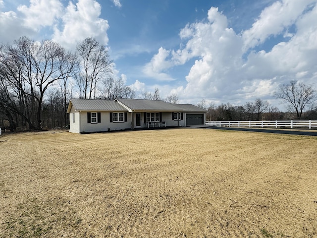 ranch-style home featuring metal roof, a garage, a front lawn, and fence