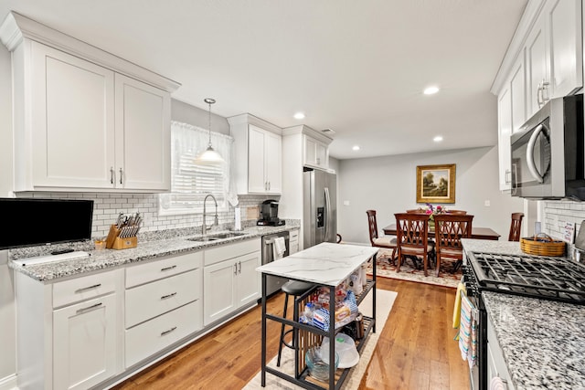 kitchen featuring a sink, stainless steel appliances, light wood-type flooring, and white cabinetry