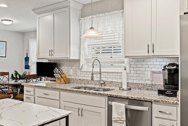 kitchen featuring a sink, stainless steel dishwasher, white cabinets, and hanging light fixtures