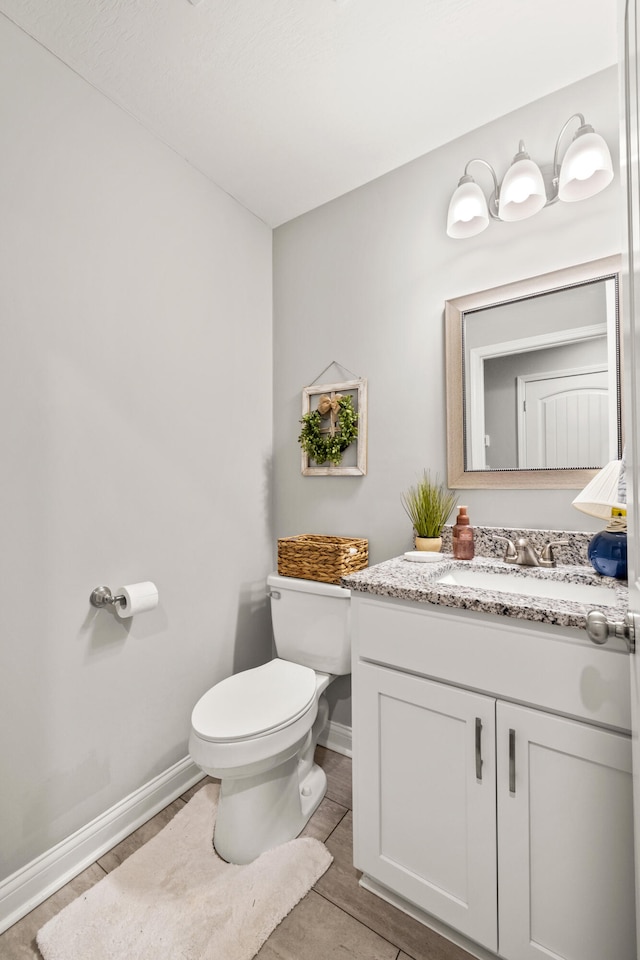 bathroom featuring vanity, toilet, and baseboards