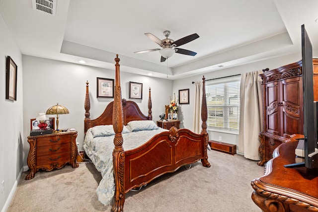 bedroom with light carpet, visible vents, a raised ceiling, and baseboards