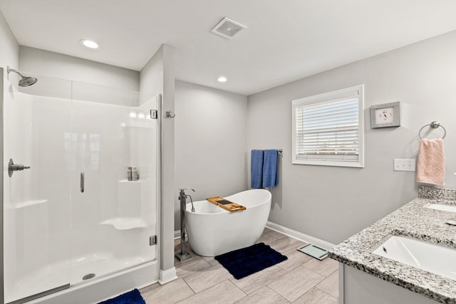 full bathroom with visible vents, a sink, a shower stall, baseboards, and a freestanding bath