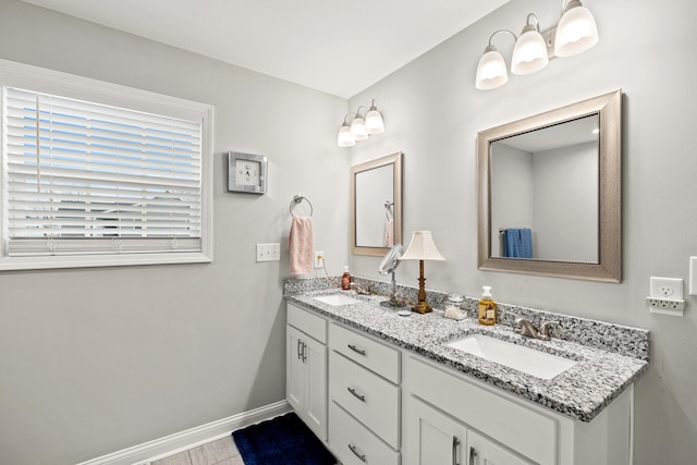 full bath with double vanity, baseboards, and a sink