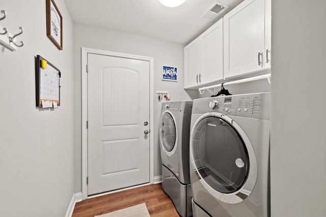 clothes washing area with light wood-type flooring, visible vents, cabinet space, baseboards, and washing machine and clothes dryer