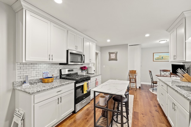 kitchen featuring white cabinetry, decorative backsplash, light wood-style flooring, and stainless steel appliances