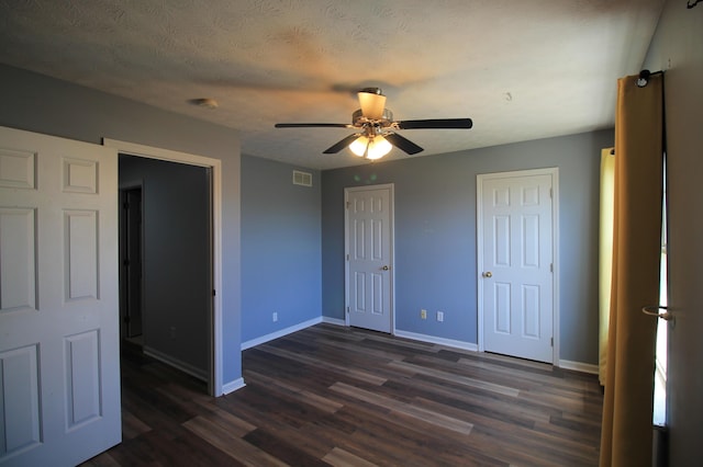 unfurnished bedroom featuring dark wood finished floors, baseboards, visible vents, and a textured ceiling