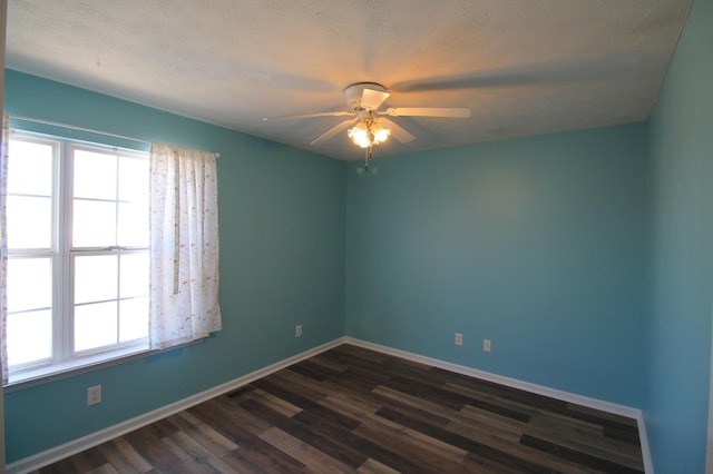 unfurnished room with a wealth of natural light, ceiling fan, baseboards, and dark wood-style flooring